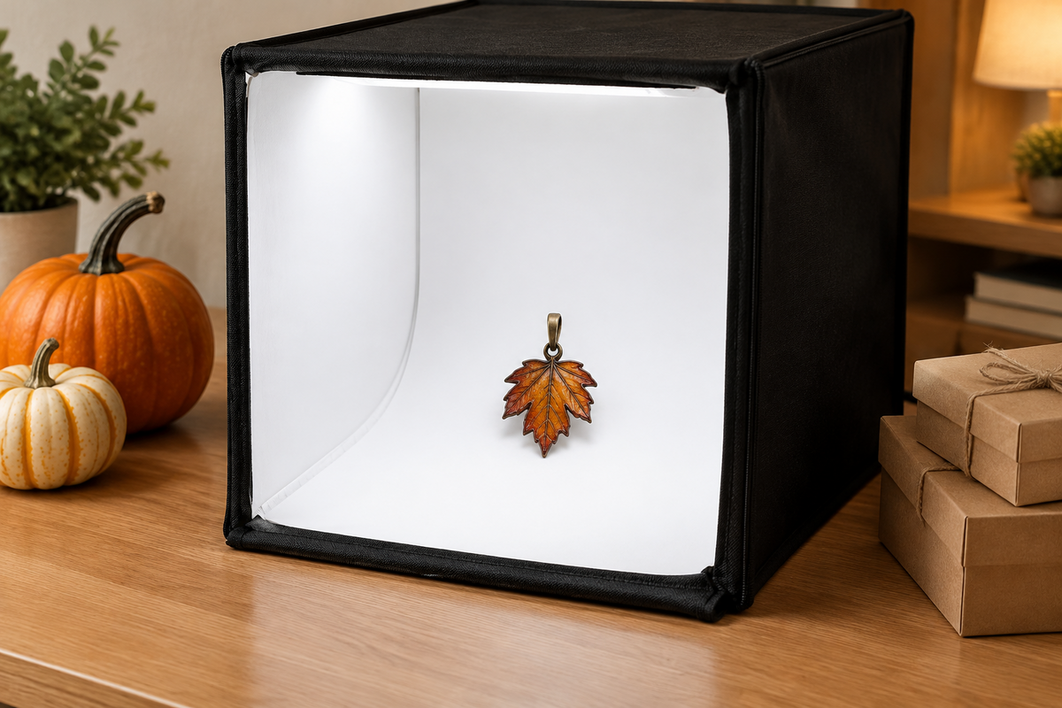Desktop photography light box illuminating a handmade autumn leaf pendant, with Thanksgiving gift packaging nearby.