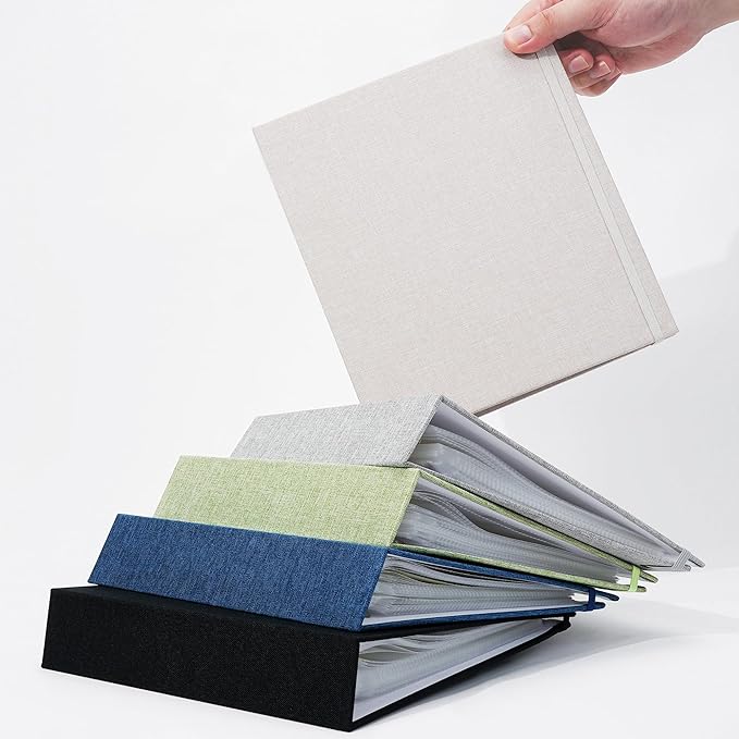 TrailMate archival photo album in beige linen, shown with assorted colorful albums stacked below.